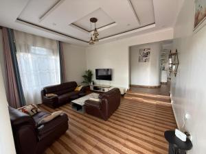 a living room with brown leather furniture and a tv at Eden house in Kigali