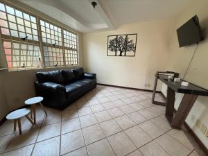 a living room with a black leather couch and a table at Mega Suíte Na Melhor Localização in Botucatu