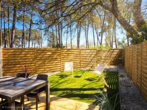 a backyard with a table and chairs and a fence at Maisonnette privative Bassin Arcachon in Le Teich
