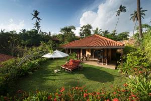 a house with an umbrella and a chair and a yard at Cape Weligama in Weligama