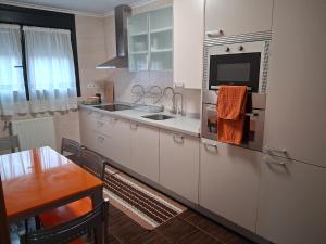 a kitchen with white cabinets and a sink and a table at Ayalga2 in Villaviciosa