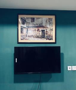 a flat screen tv on a blue wall with a painting at SmartStay Residences in Rawalpindi