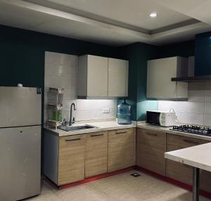 a kitchen with wooden cabinets and a white refrigerator at SmartStay Residences in Rawalpindi