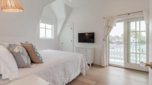 a white bedroom with a bed and a tv at The Ocean Loft At Kings in Cape May