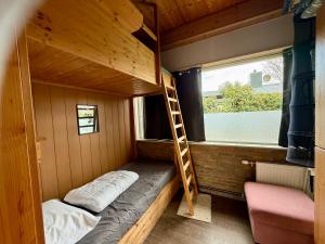 a bunk bed in a tiny house with a ladder at Bungalow Marita in Julianadorp