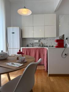 a kitchen with white cabinets and a wooden table with chairs at I Maltesi apartment in Sassari