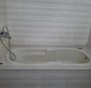 a white bath tub with a shower in a bathroom at Umbrella Guest House - Meenakshi Suite in Madurai