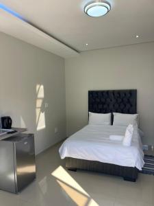 a bedroom with a white bed with a black headboard at Premium View Guesthouse in Windhoek +12 photos