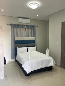 a bedroom with a bed with white sheets and pillows at Premium View Guesthouse in Windhoek