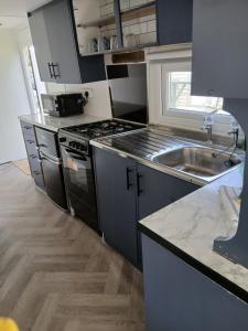 a kitchen with a stove and a sink at Family friendly static in Pwllheli