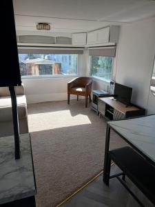 a living room with a bed and a desk and a chair at Family friendly static in Pwllheli