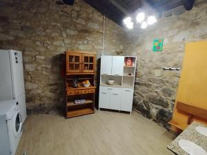 a kitchen with white appliances and a stone wall at refuxio de pambre in Palas de Rei