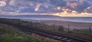 a train track next to a beach with the ocean at Downhill Beach Studio Suite in Coleraine +5 photos