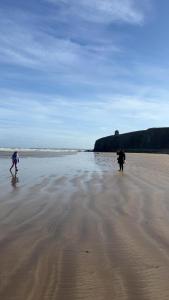 two people walking on a beach near the water at Downhill Beach Studio Suite in Coleraine