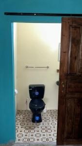 a bathroom with a black toilet in a room at Habitaciones Lala in Las Peñitas