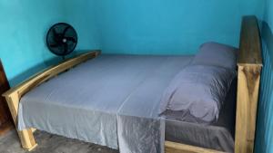 a bed in a room with a blue wall at Habitaciones Lala in Las Peñitas