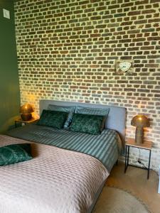 a bedroom with two beds and a brick wall at Gastenverblijf Het Groene Hart in Lanaken
