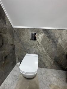 a white toilet in a bathroom with a stone wall at Вича апартаменти in Sasivka +13 photos