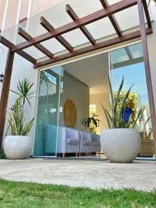 a house with glass doors and two potted plants at Pousada Porto Rio in Parnaíba