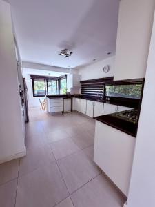 a large kitchen with white cabinets and a tile floor at Casa con piscina en Estancias del Pilar, 3 dormitorios, jardín y parrilla in Pilar +30 photos