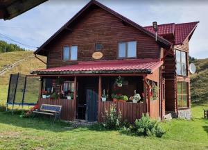 a wooden house with a bench in front of it at Plaiul Carpatin in Fundăţica