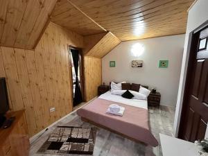 a bedroom with a large bed in a room with wooden walls at Plaiul Carpatin in Fundăţica