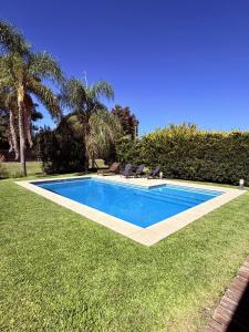 a swimming pool in a yard with palm trees at Casa con piscina en Estancias del Pilar, 3 dormitorios, jardín y parrilla in Pilar