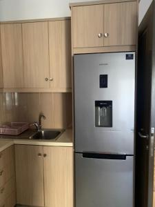 a stainless steel refrigerator in a kitchen with wooden cabinets at Golem Central Stay in Golem