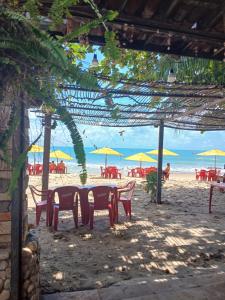 a beach with tables and chairs and yellow umbrellas at Pé na praia - Barraca da Márcia in Paracuru
