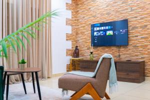 a living room with a television on a brick wall at Suite Kimia - Chic T2, Rue Des Jardins, Cocody, Vallon, Abidjan in Abidjan