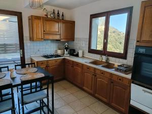 a kitchen with wooden cabinets and a table with chairs at A Tana di a Volpe in Alzetu