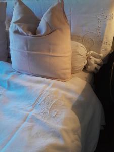 a bed with white sheets and pillows at la maison de Royer in Meuzac