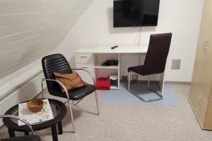 a room with a desk and two chairs and a tv at Ferienhaus "Harzblick" in Halberstadt