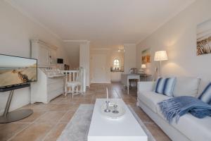 a living room with a white couch and a tv at Appartement Lycka in Keitum