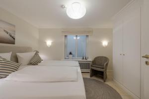 a white bedroom with two beds and a window at Appartement Lycka in Keitum