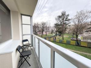 two chairs on a balcony with a view of a park at Green Oasis Apartment in Myslava