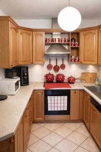 a kitchen with wooden cabinets and a red stove top oven at Kuća za odmor Petra in Erdut