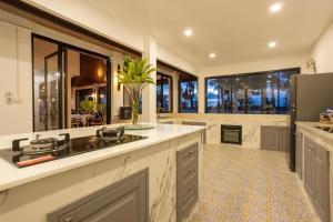 a large kitchen with a sink and a refrigerator at Sirinary Villa - Natai Phangnga in Ban Na Tai