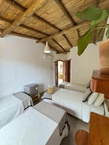 three beds in a room with wooden ceilings at Pousada Dendê Caraiva in Caraíva