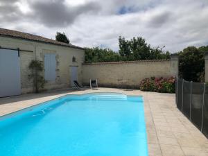 a large blue swimming pool in a yard at Chai Léopold in Surgères