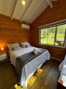 a bedroom with a large bed and a large window at Quinta Terra Sagrada in Urubici