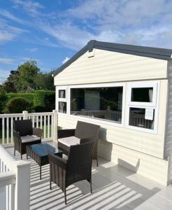 a white house with chairs and a table on a deck at 609 Sycamore Forest in Newquay