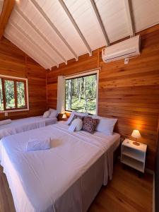 two beds in a room with wooden walls at Quinta Terra Sagrada in Urubici