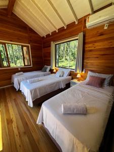 three beds in a room with wooden walls at Quinta Terra Sagrada in Urubici
