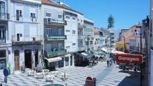a city street with tables and chairs and buildings at Luz de Cacilhas Apt, few steps away from Lisboa! in Almada
