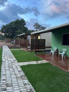 a house with chairs and a patio and grass at Chalés ninhos do cerrado in Cavalcante