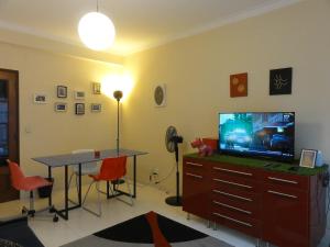 a living room with a television and a table and chairs at Luz de Cacilhas Apt, few steps away from Lisboa! in Almada