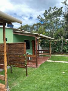 a green house with a wooden fence in front of it at Chalés ninhos do cerrado in Cavalcante