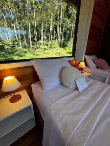 a room with two beds and a large window at Quinta Terra Sagrada in Urubici