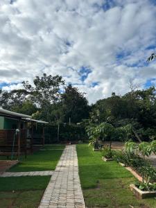 a garden with a brick path in front of a house at Chalés ninhos do cerrado in Cavalcante +3 photos